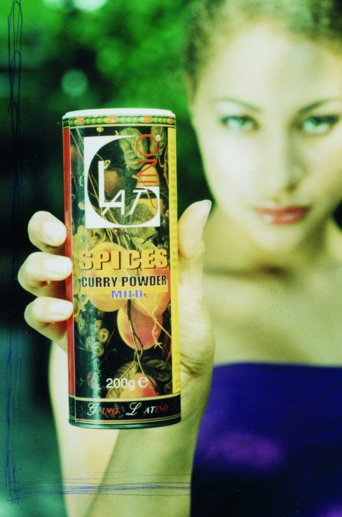 Woman holding a tin of Gino Latino mild curry powder