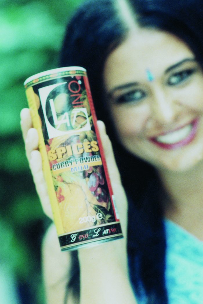 Woman smiling with a tin of Gino Latino curry powder